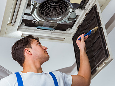 Manutenzione filtri aria trento Tecnico pulisce il filtro di un climatizzatore a soffitto