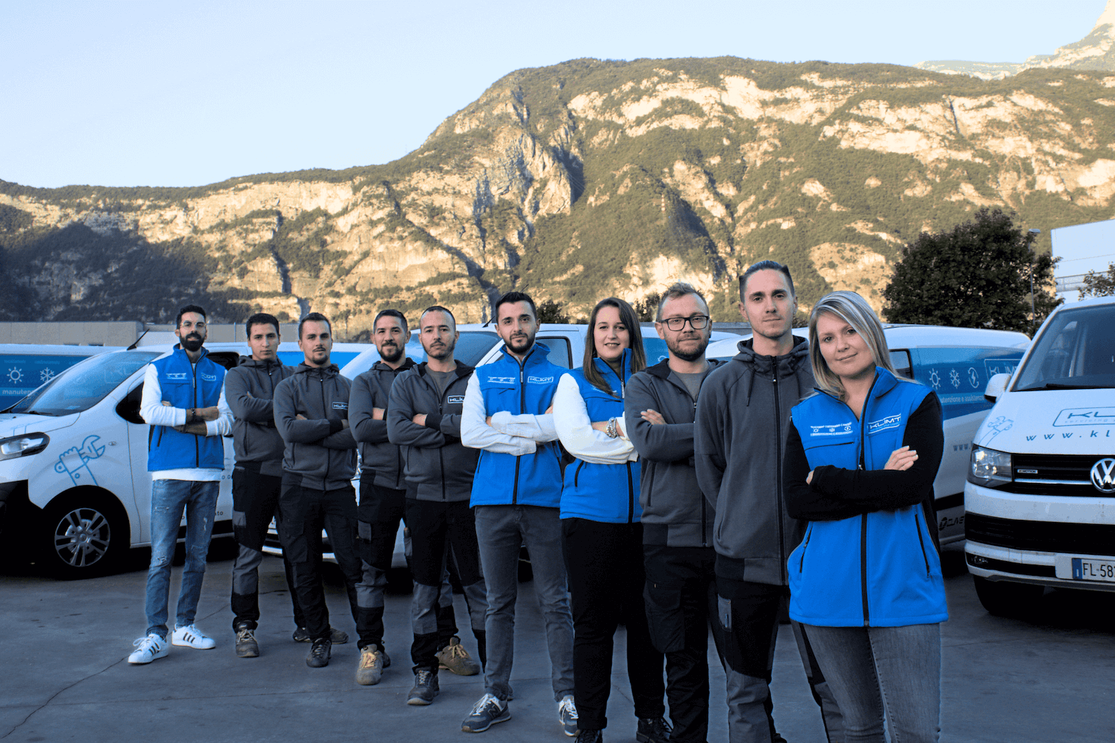 Dieci membri del team Klimt davanti ai furgoni aziendali in montagna